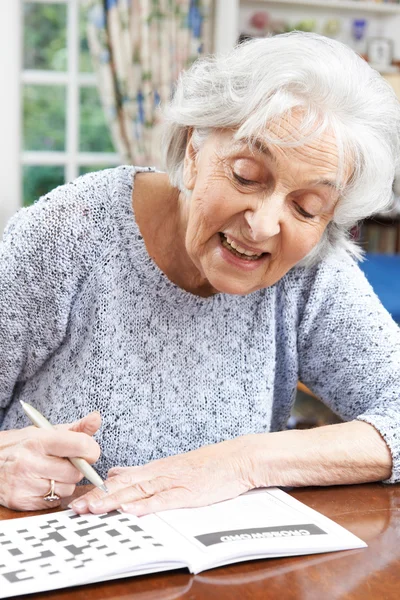 Старша жінка розслабляється з кросвордом головоломки вдома — стокове фото