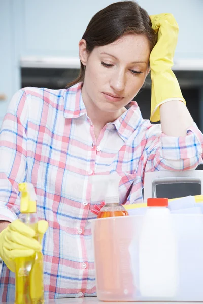 Mujer infeliz rodeada de productos de limpieza en casa — Foto de Stock