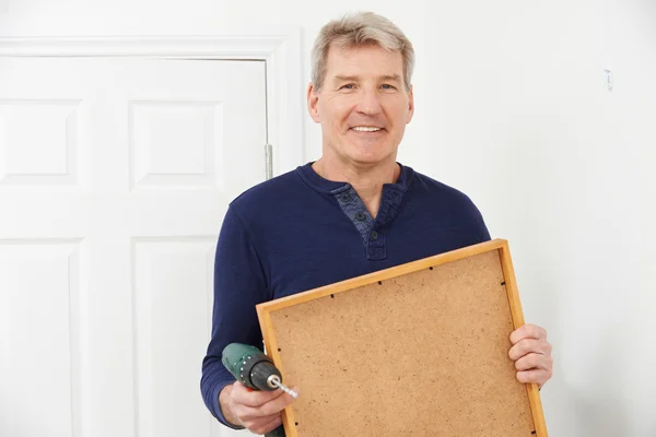 Mature Man Drilling Wall To Hang Picture Frame — Stock fotografie