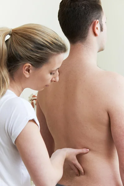 Женщина-остеопат лечит мужского пациента с проблемой спины — стоковое фото