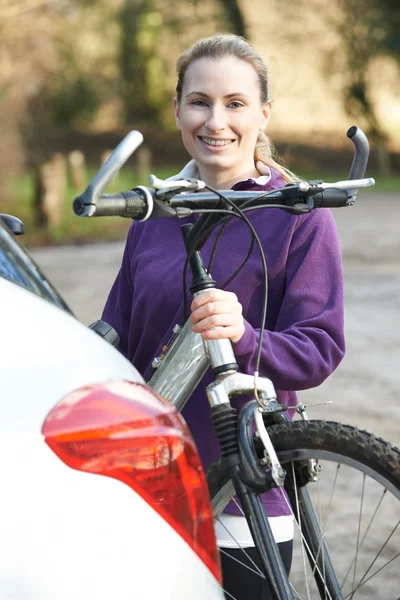 Mujer ciclista tomando bicicleta de montaña desde el bastidor en el coche — Foto de Stock