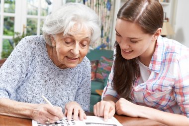 Teenage Granddaughter Helping Grandmother With Crossword Puzzle clipart