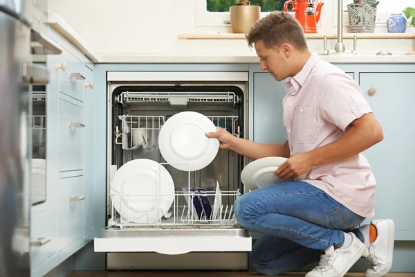 Mann lädt Geschirrspüler in Küche — Stockfoto