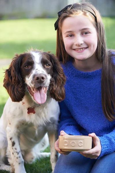 Mädchen füttert Hund Spaniel aus Schüssel im Garten — Stockfoto