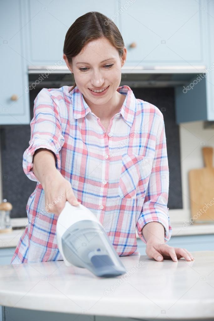 Woman Cleaning Kitchen Using Hand Held Vacuum Cleaner