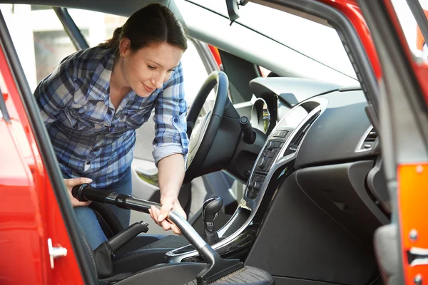 Mujer limpieza interior del coche usando aspiradora — Foto de Stock