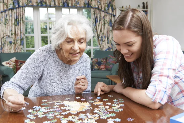 ジグソー パズルで 10 代の孫娘支援祖母 — ストック写真