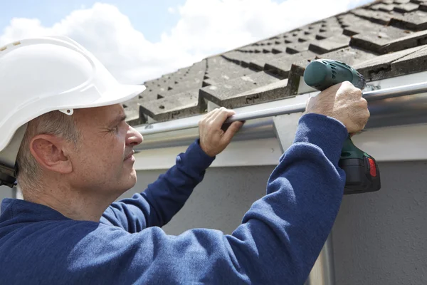 Handwerker ersetzt Dachrinnen an Hausfassade — Stockfoto