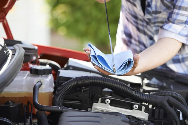 Közeli kép a nő ellenőrzése az autó motor olaj-szint a tesztcsík — Stock Fotó