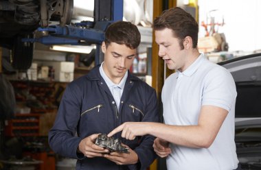 Mekanik, çırakların motoru tamir etmesine yardım ediyor