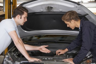 Mekanik, çırakların motoru tamir etmesine yardım ediyor