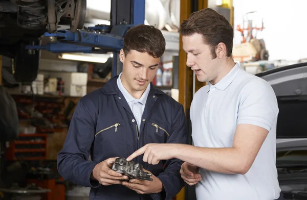 Mechanik pomáhá učedníkovi opravit motor — Stock fotografie