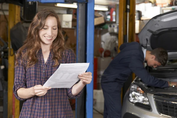 Cliente feminino na oficina de reparação automática satisfeito com Bill para carro — Fotografia de Stock