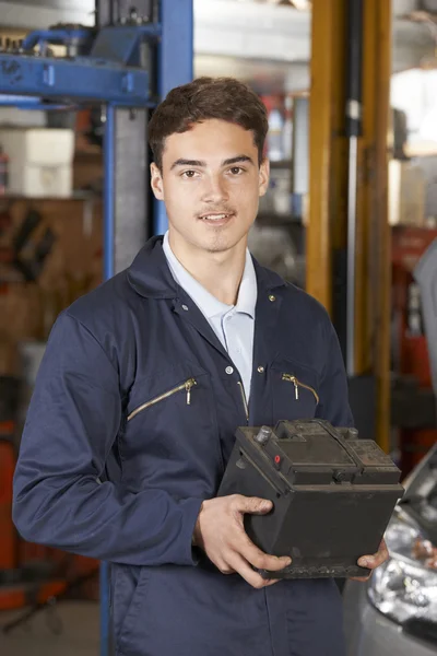 Aprendiz mecánico que sostiene la batería del coche en taller de reparación de automóviles — Foto de Stock