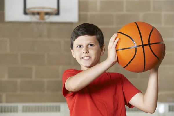 Junge schießt bei Basketballspiel in Schulsporthalle — Stockfoto