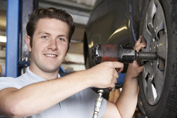 Mechanik w garażu przy użyciu powietrza młotek na koła samochodu — Zdjęcie stockowe