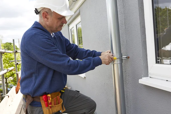 Handwerker ersetzt Dachrinnen an Hausfassade — Stockfoto