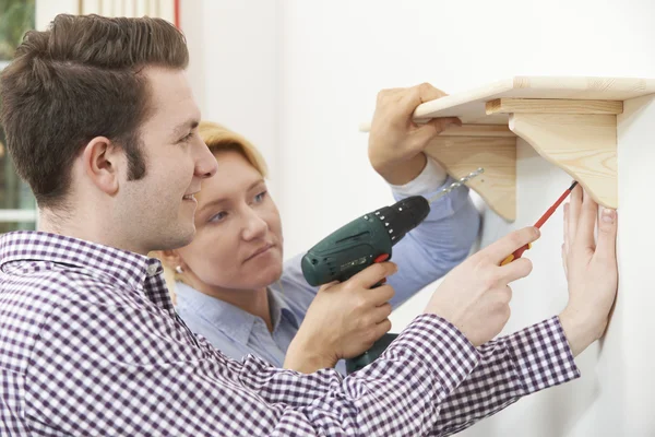 Couple mettre en place étagère en bois ensemble à la maison — Photo