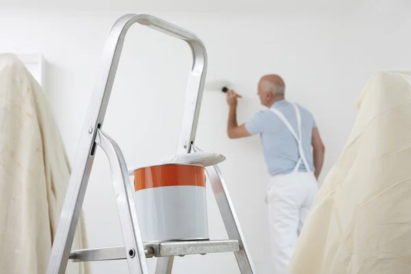 Man Decorating Room With Can Of Paint And Brush In Foreground Stock Image