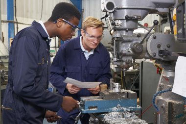 Engineer Showing Apprentice How to Use Drill In Factory clipart