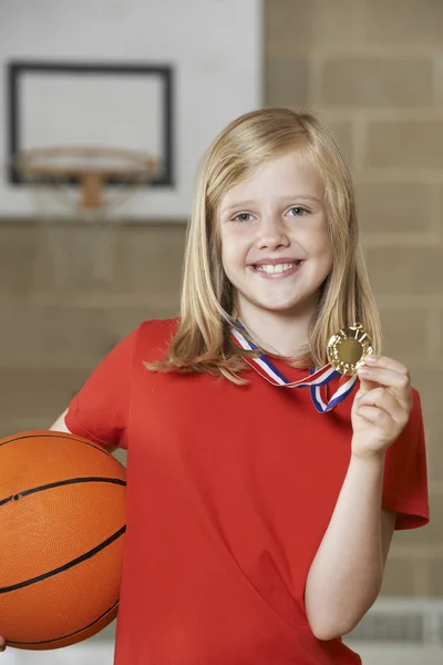 Dívka drží basketbal a medaile v tělocvičně školy — Stock fotografie