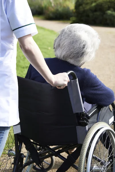 Primo piano di carriera spingendo donna anziana in sedia a rotelle — Foto Stock