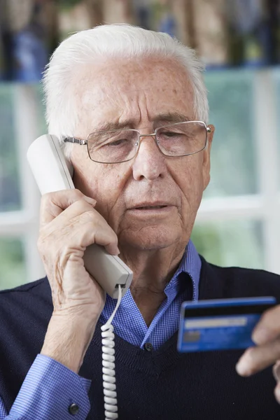 Старший чоловік надає реквізити кредитної картки на телефоні — стокове фото