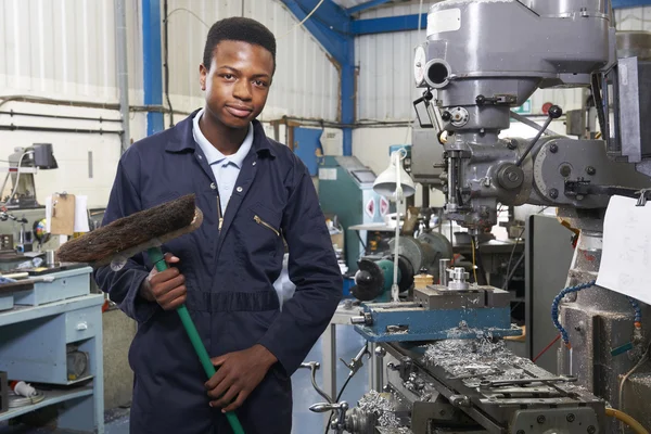 Lärling i tekniska fabrik sopa golv — Stockfoto