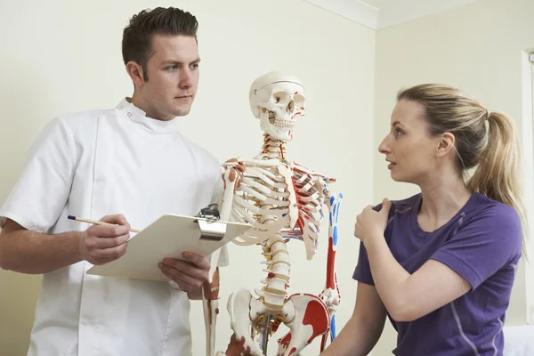 Kvinnlig Patient som beskriver axelskada till osteopat — Stockfoto