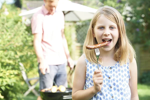 Menina comendo salsicha no churrasco da família — Fotografia de Stock