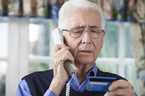 Homme âgé donnant des détails de carte de crédit au téléphone — Photo