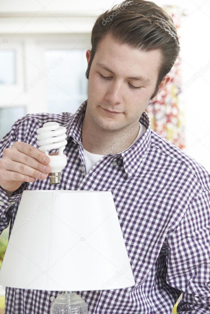 Man Putting Low Energy Lightbulb Into Lamp At Home — Stock Photo