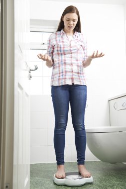 Mutsuz genç kız banyo Baskülleri üzerinde ayakta