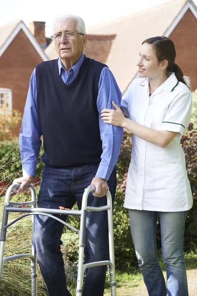 Vårdaren att hjälpa äldre mannen till promenad i trädgården med Walking stomme — Stockfoto