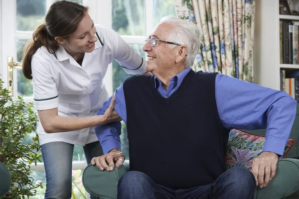 Care Worker Aiutare l'uomo anziano ad alzarsi dalla sedia — Foto Stock