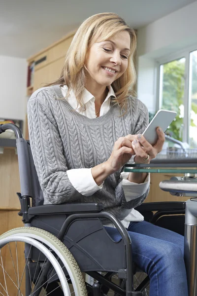 Женщина-инвалид в инвалидной коляске смс на мобильном телефоне дома — стоковое фото