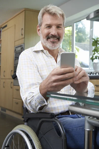 Handikappade mannen i rullstol skicka SMS på mobiltelefon hemma — Stockfoto