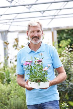 Portrait Of Male Sales Assistant At Garden Center Holding Plants clipart