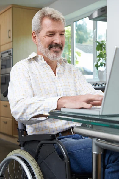 残疾的男子坐轮椅在家里使用笔记本电脑 — 图库照片