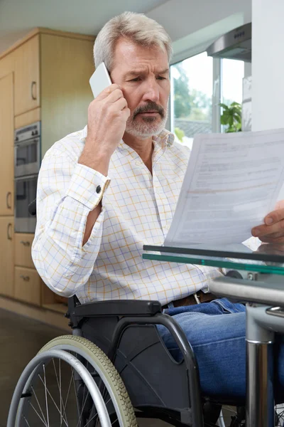 Homme frustré en fauteuil roulant faisant un appel téléphonique tout en lisant Le — Photo