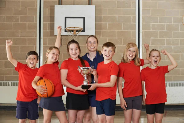 Equipe de esportes da escola vitoriosa com troféu no ginásio — Fotografia de Stock