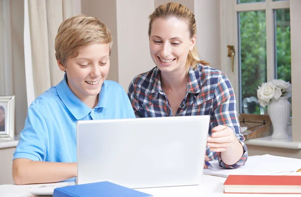 Tutor casero femenino que ayuda al muchacho con estudios usando computadora portátil —  Fotos de Stock