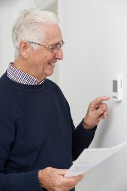 Merkezi Isıtma Thermosta ayarlama Bill ile gülümseyen kıdemli adam