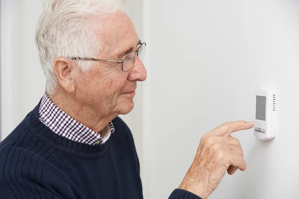 Homme âgé souriant Réglage du thermostat de chauffage central — Photo