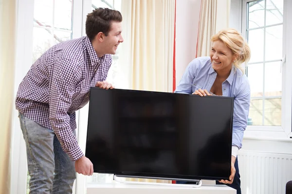 Pareja emocionada configurando nueva televisión en casa — Foto de Stock