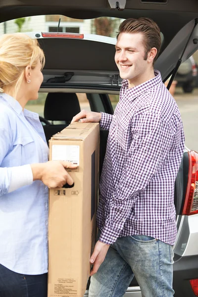 Paar lossen nieuwe televisie uit auto kofferbak — Stockfoto