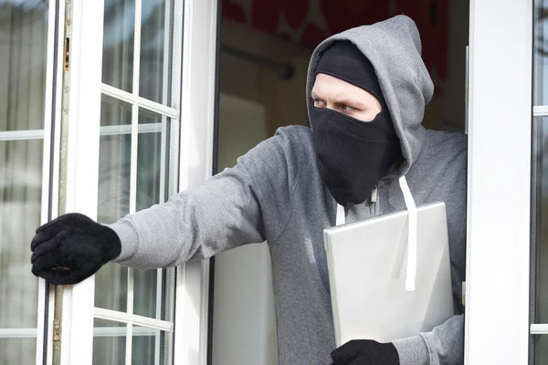 Assaltante invadindo casa e roubando computador portátil — Fotografia de Stock