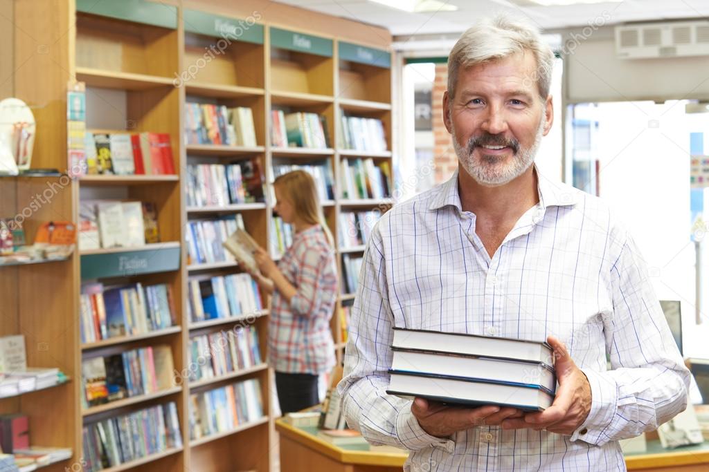 Portrait Of Male Bookstore Owner With Customer In Background