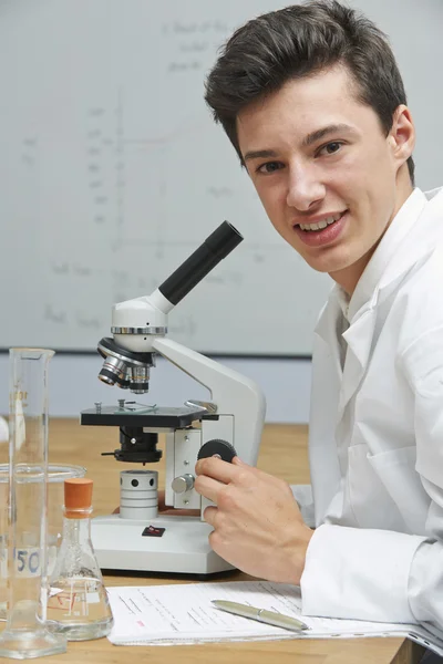 Retrato de aluno masculino usando microscópio no laboratório de ciências — Fotografia de Stock