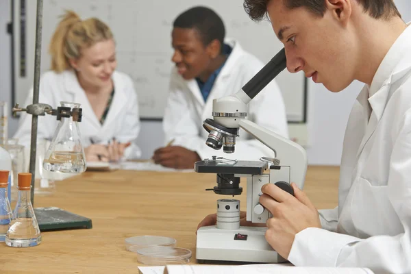 Студенти-підлітки в класі науки за допомогою мікроскопа — стокове фото